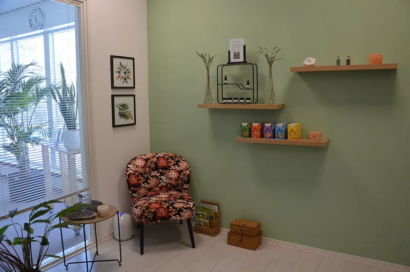 Hoek van de salon met zoutlamp, planten en wandplanken
